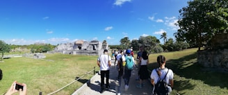A group of happy tourists exploring a historic site under a clear blue sky.