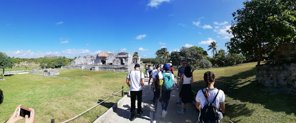 A group of happy tourists exploring a historic site under a clear blue sky.