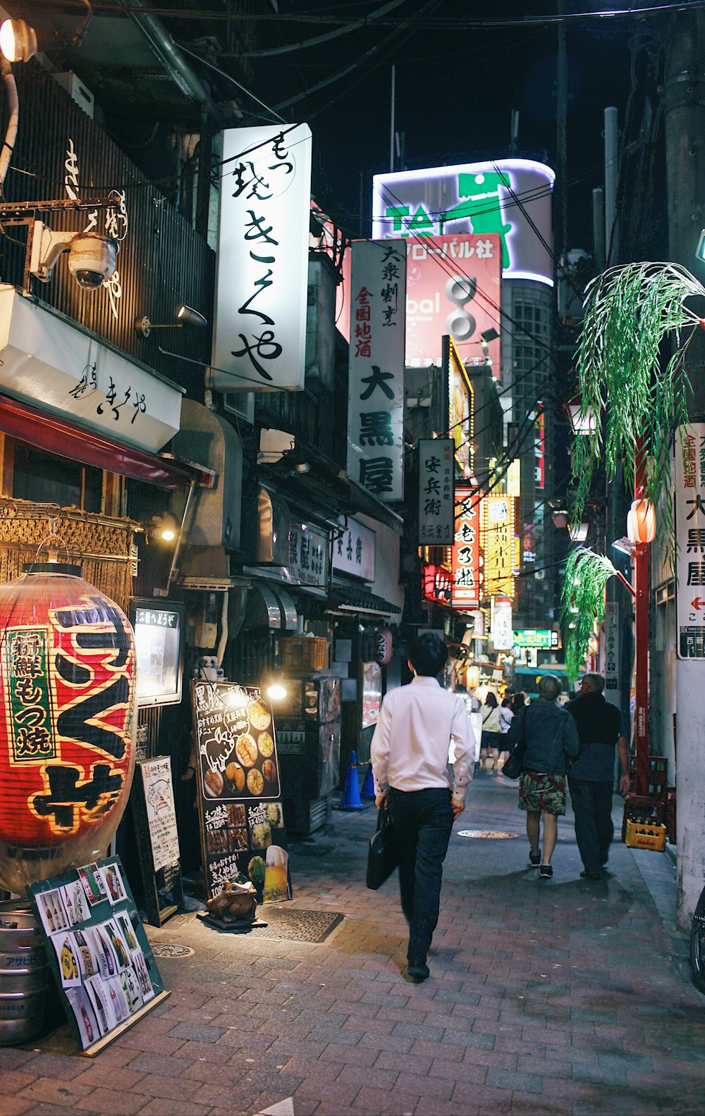 people walking on paver brick pathway between commercial stores during nighttime