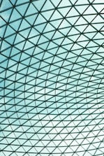 A large glass roof structure with a grid design, consisting of numerous panes of clear glass held together by a metal framework creating a geometric pattern.