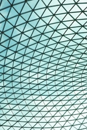 A large glass roof structure with a grid design, consisting of numerous panes of clear glass held together by a metal framework creating a geometric pattern.
