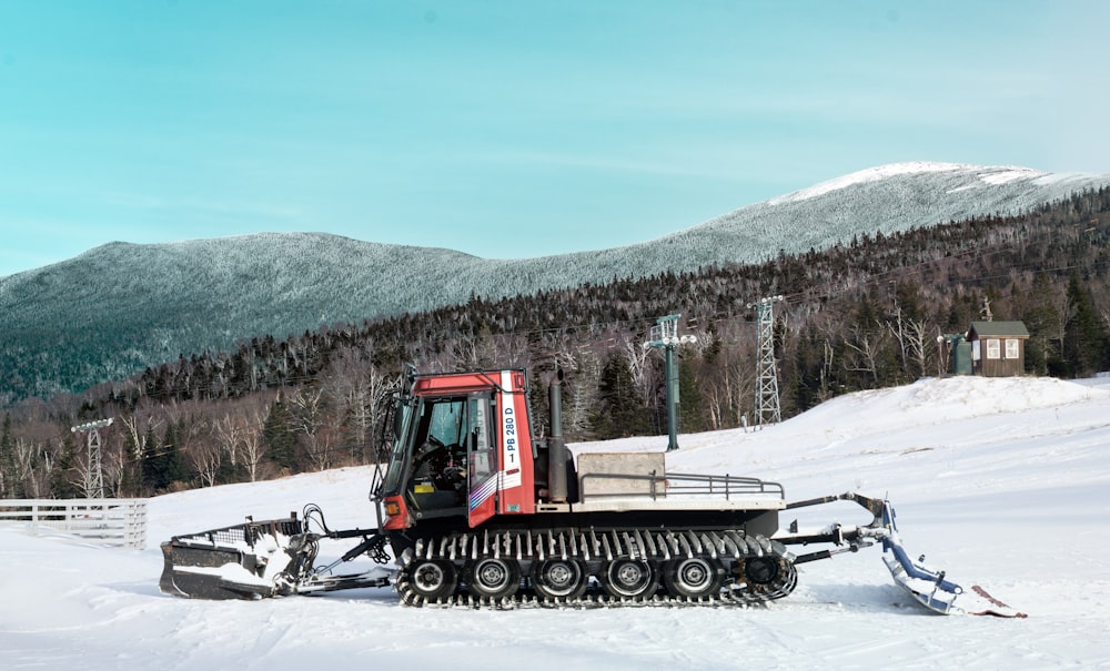 red snow bulldozer on snow-covered mountain during daytime