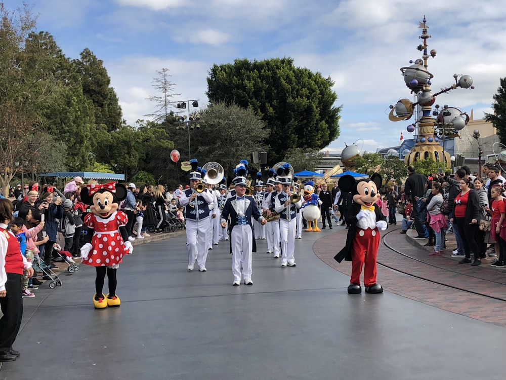 Mickey and Minni Mouse walking on street together with the marching band