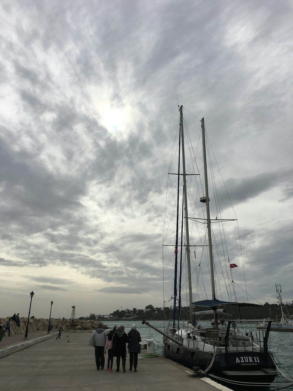 four persons standing on dock near boat at daytime