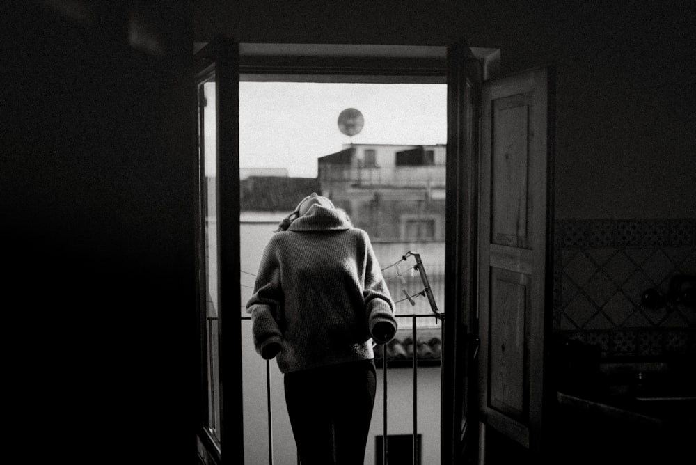 grayscale of woman standing in front of door