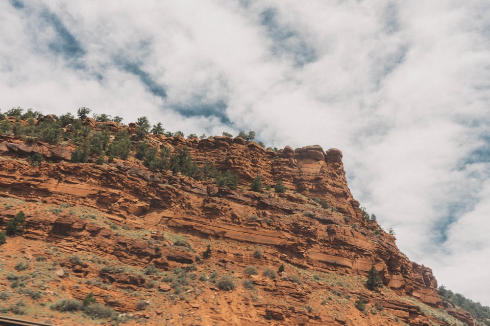 low-angle photography of brown mountain under cloudy sky during daytime