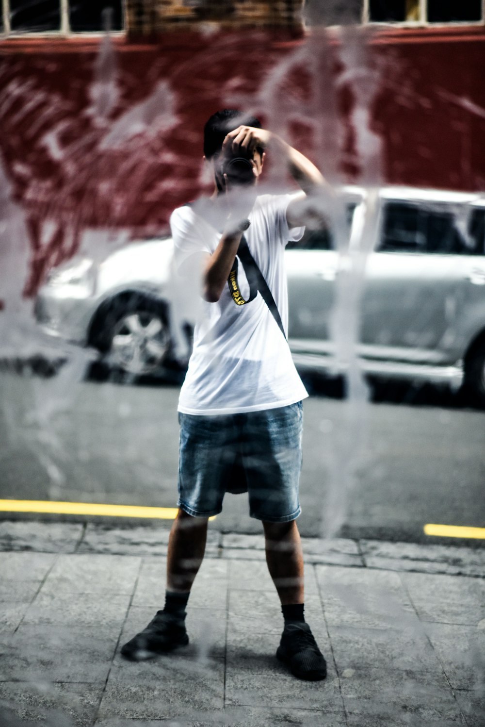 person in white t-shirt with blue and white shorts taking photo using camera