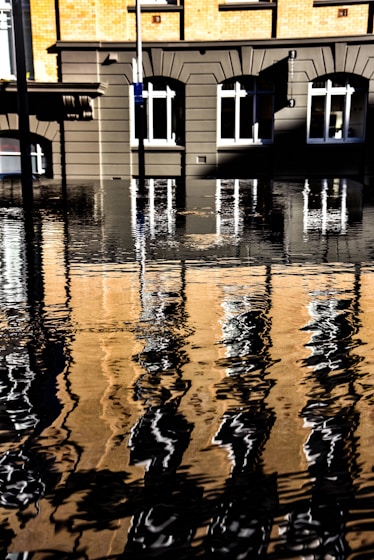 brown and yellow concrete building near body of water with self reflection