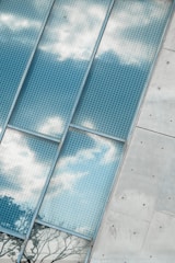 Close-up of a modern building facade featuring perforated metal panels with sunlight filtering through.