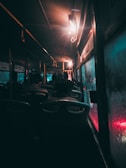 A group of passengers boarding a modern bus under a moody evening sky.