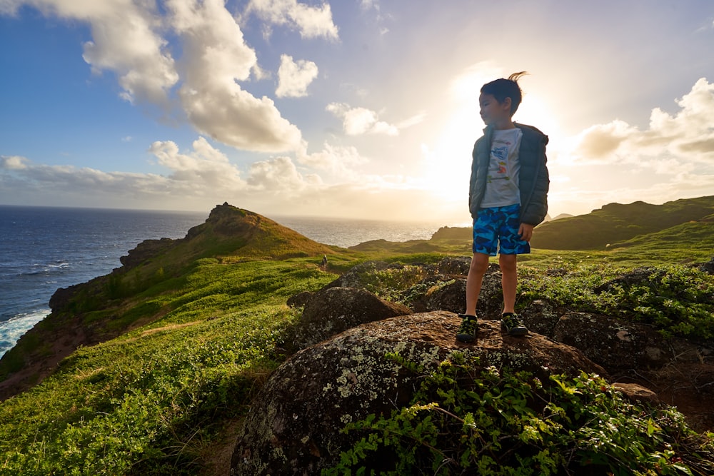 Junge steht auf einem Felsen mit Blick auf das Meer