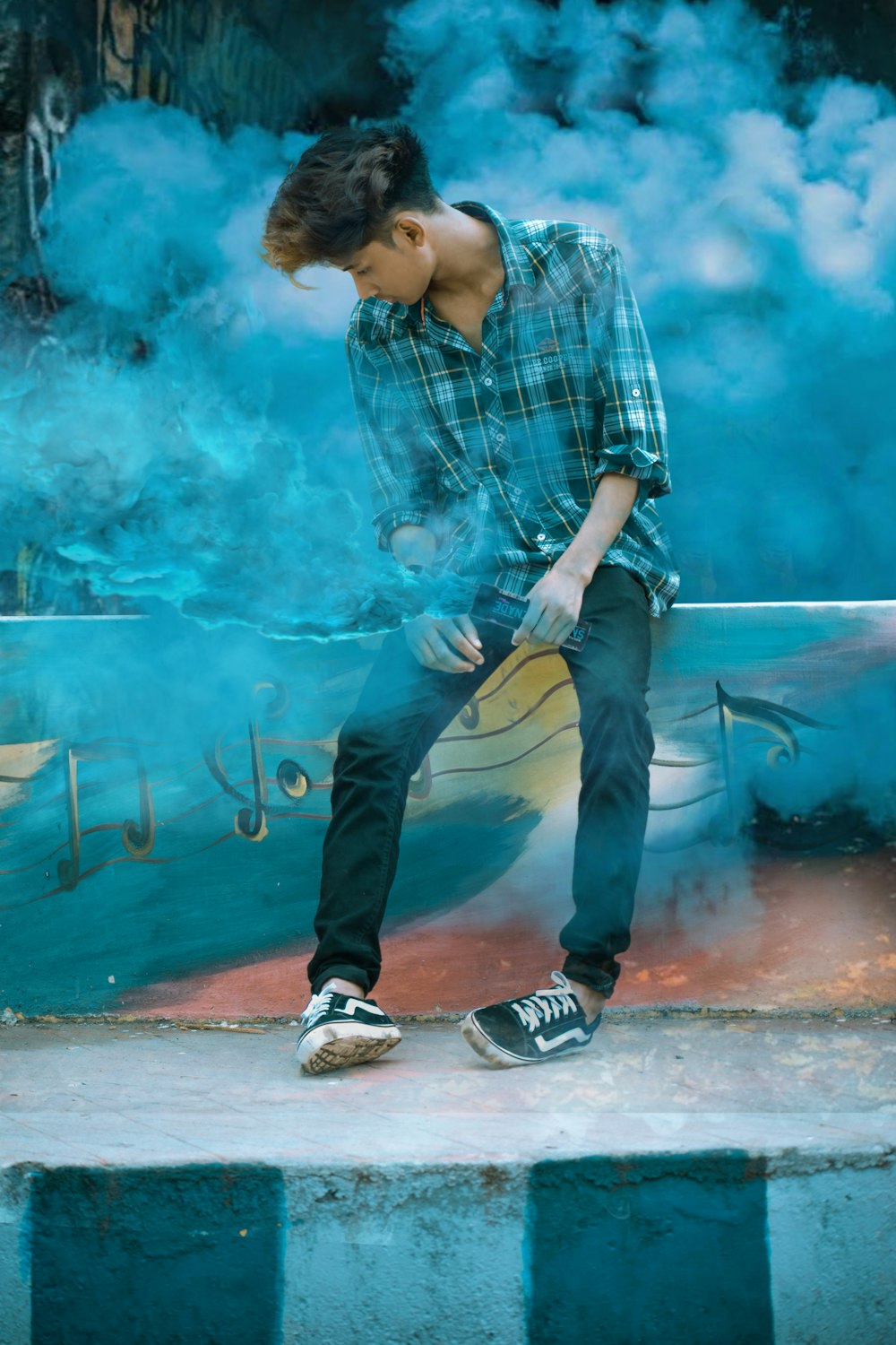 man sitting on concrete ledge with blue smoke effect