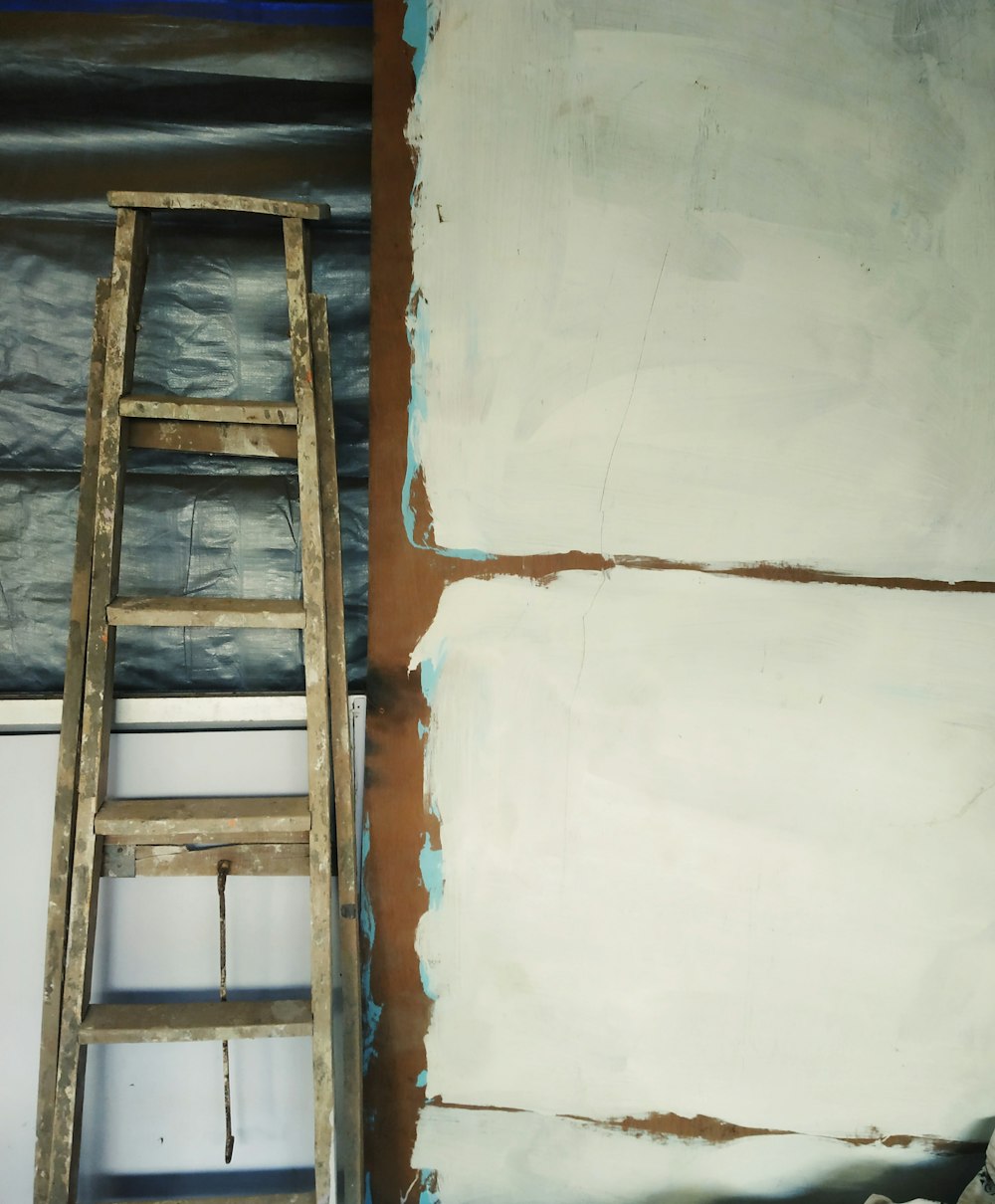 escalera de madera gris apoyada en un gabinete blanco