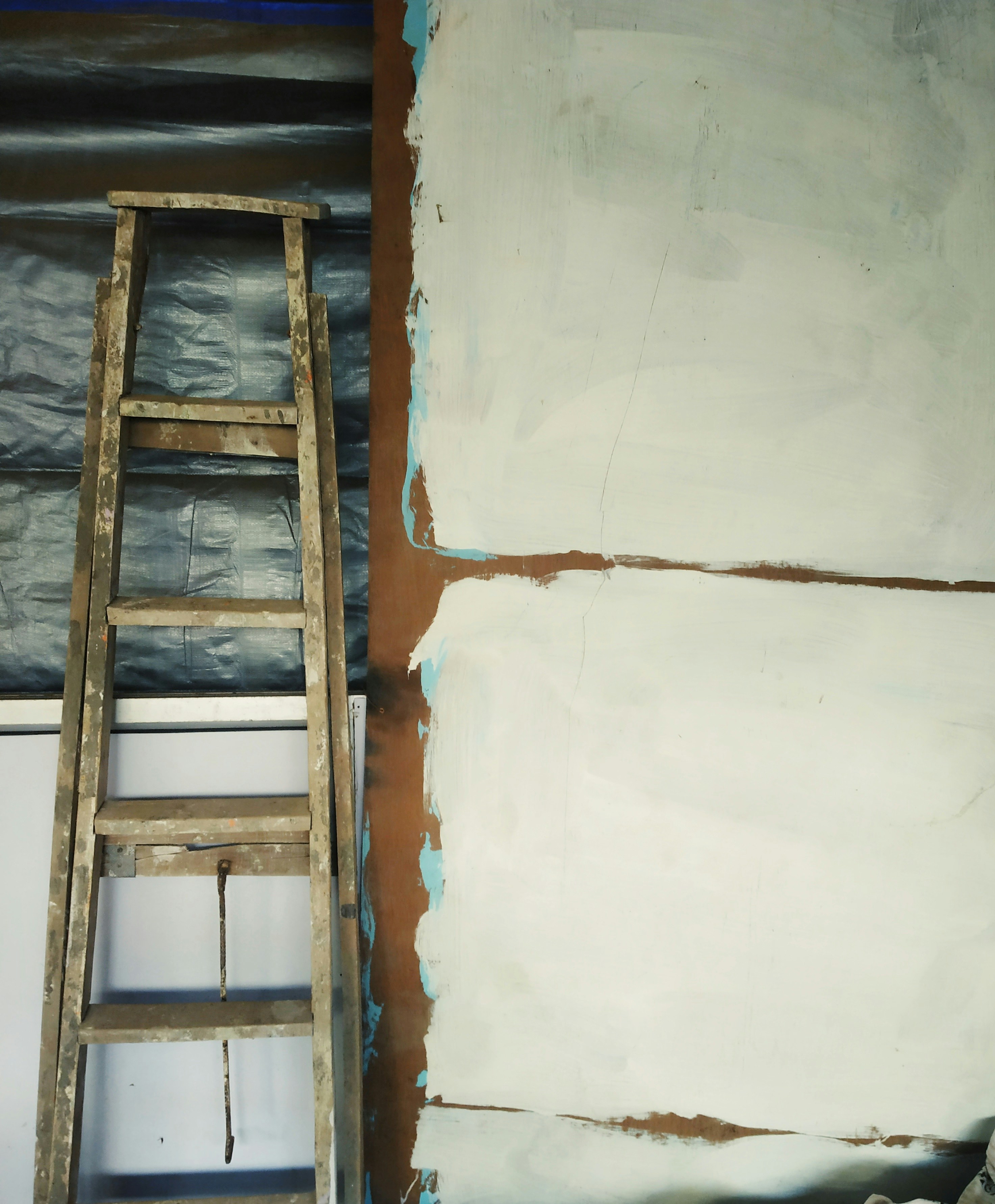 Wooden ladder with the wooden white colored plank or board placed beside it
