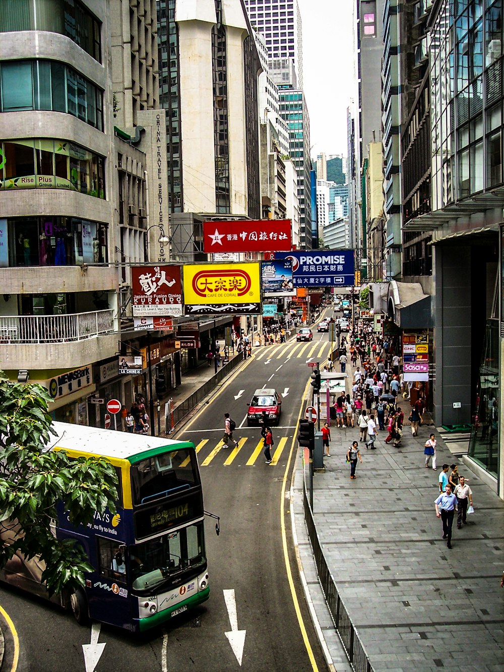 people on sidewalk and bus on street near building with signages