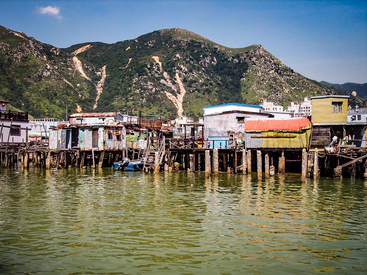 Stilt houses over the water at Tai O, with a green, rocky hill behind