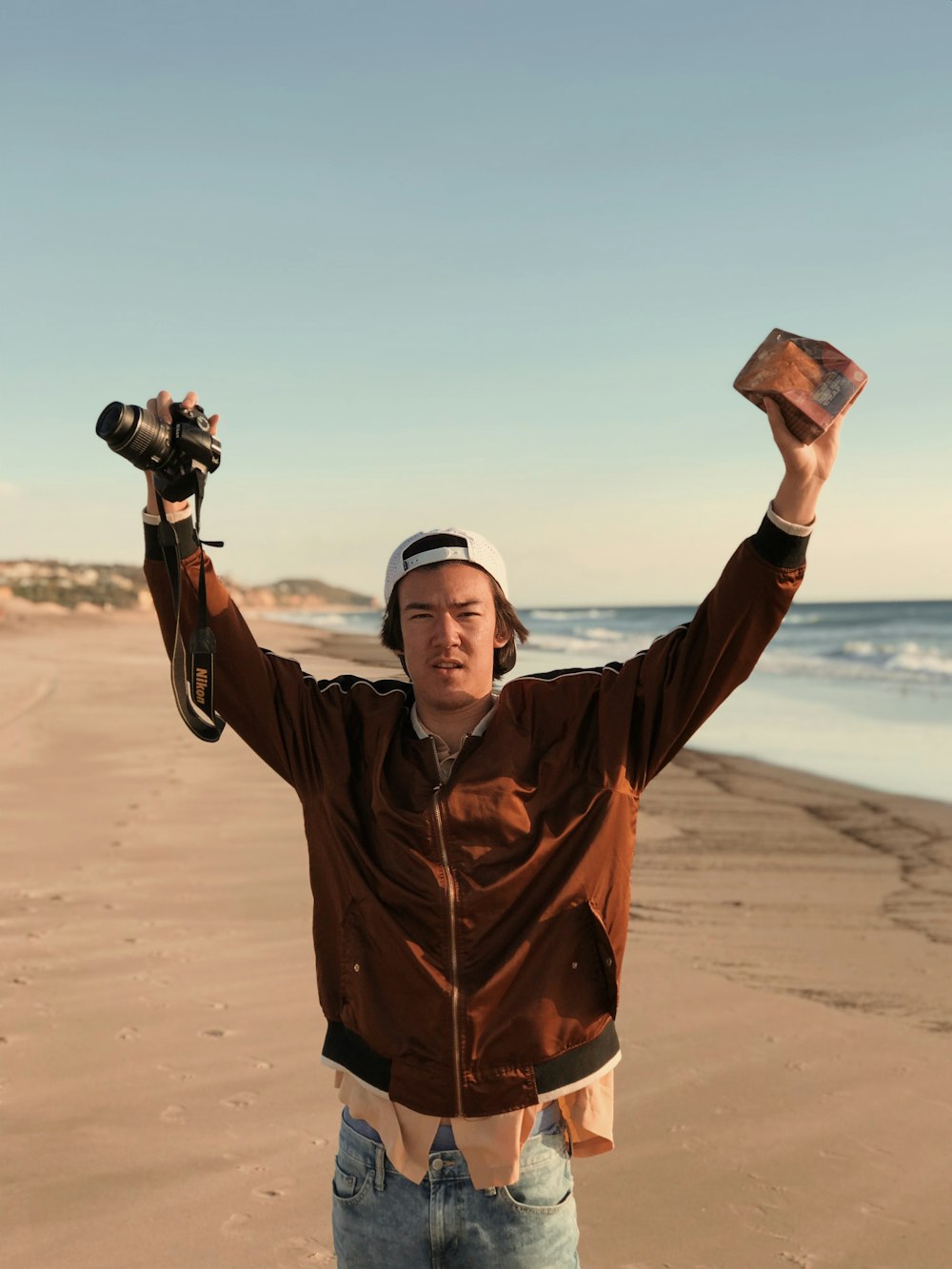 man holding DSLR camera near body of water during daytime