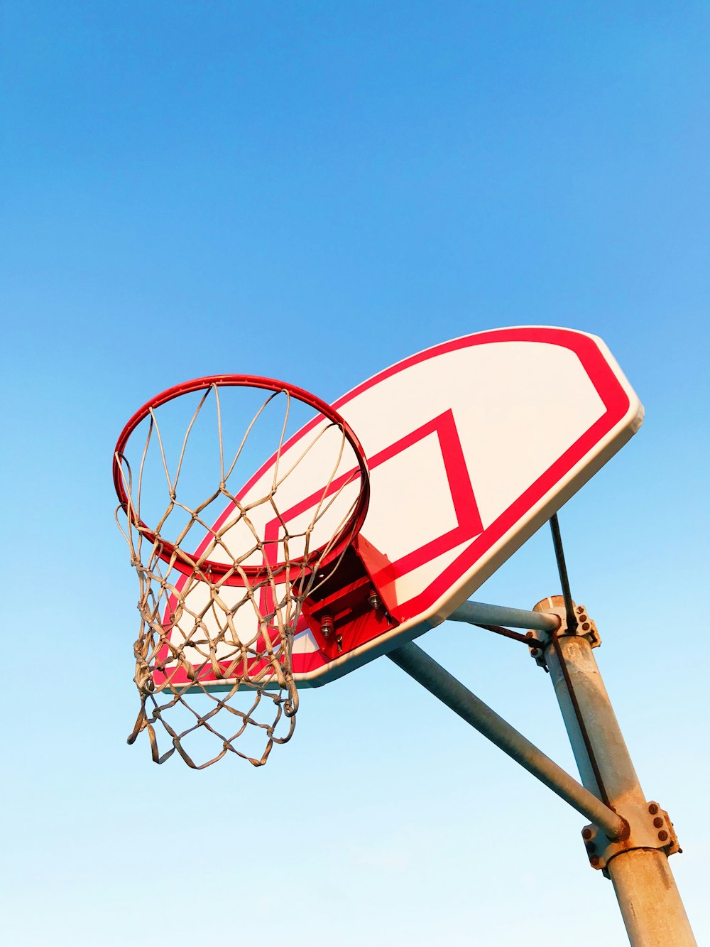 low-angel photography of white and red basketball hoop during daytime