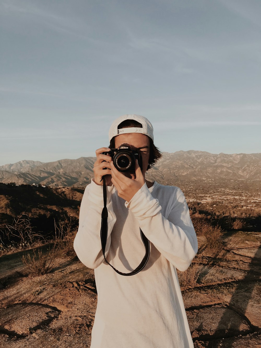 man holding camera standing near mountain ranges