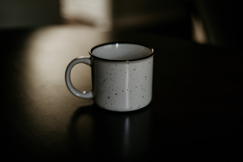 white and black ceramic cup on black surface