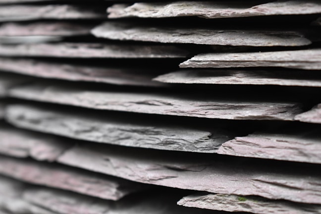 Close-up of smooth green slate stones stacked neatly in a sunlit quarry.