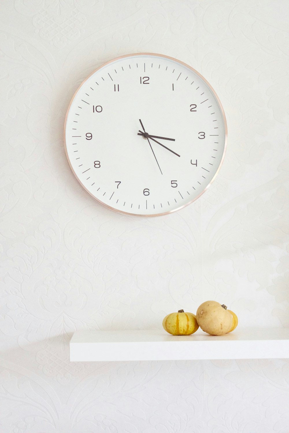 two pumpkins on table below wall clock