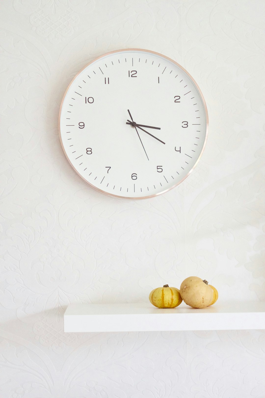  two pumpkins on table below wall clock clock