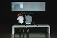 A couple watching a personalized audiovisual story on a screen.