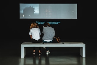 A couple watching a personalized audiovisual story on a screen.