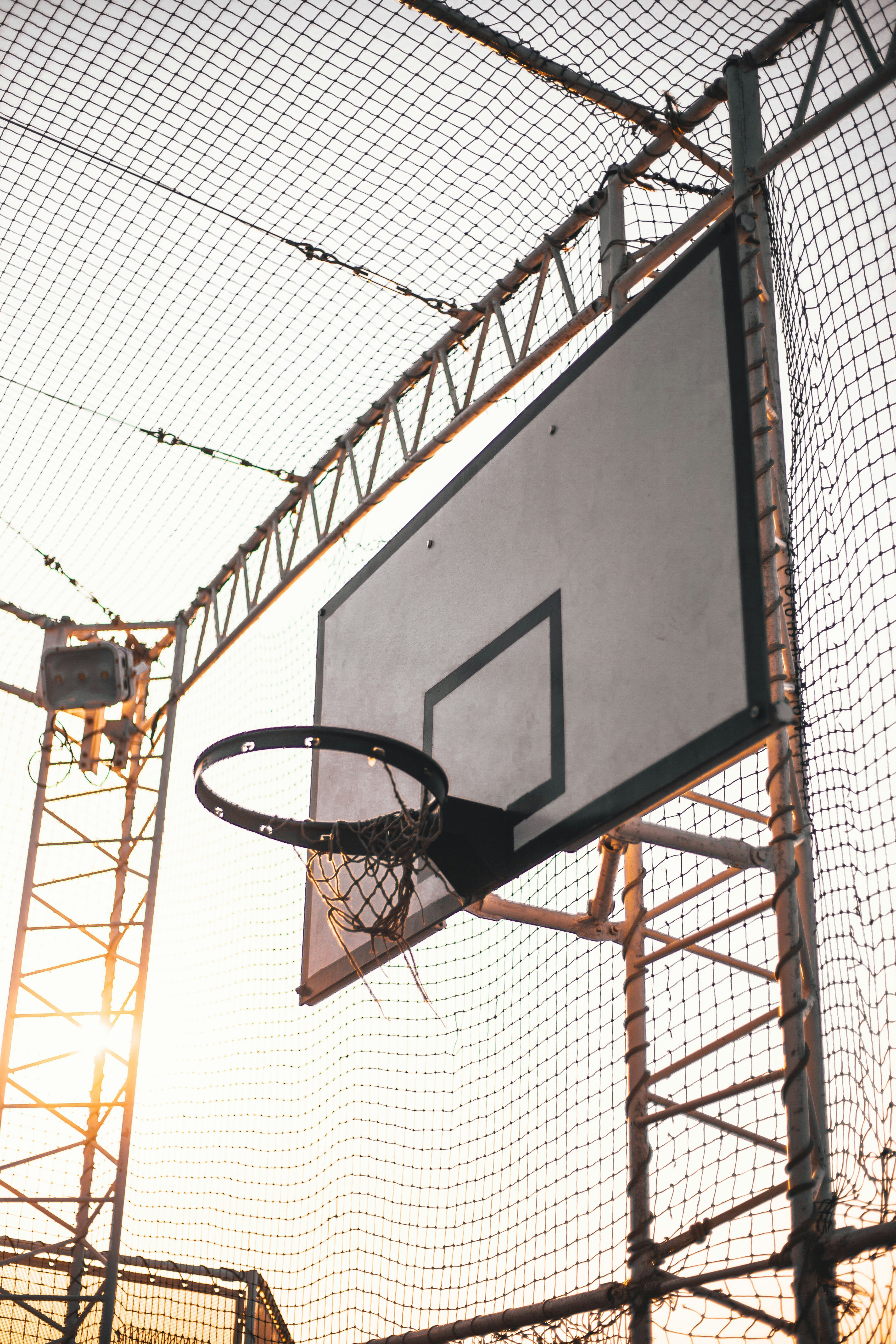 grey basketball system inside net covered court photo Free Hoop Image
