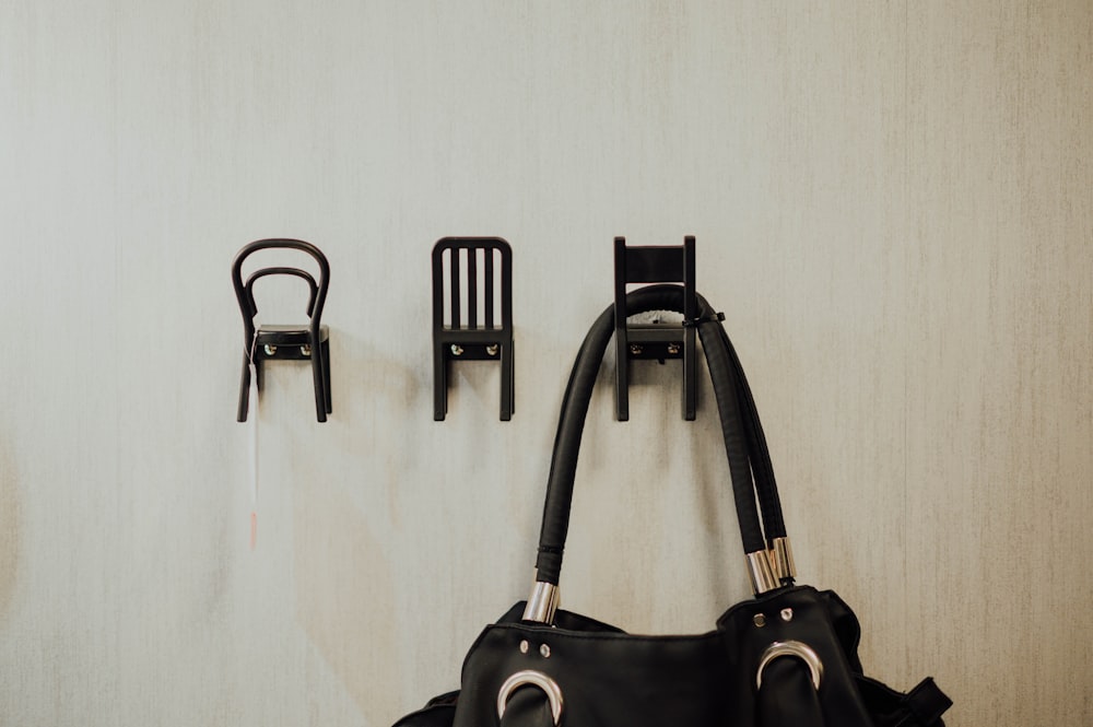 a black purse hanging on a wall next to a pair of chairs