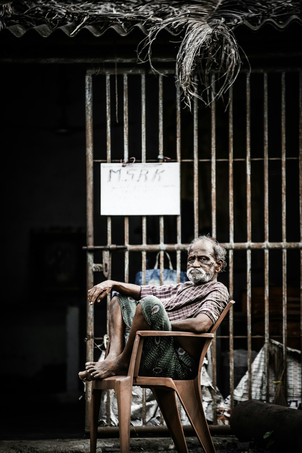 man sitting on monobloc chair outside