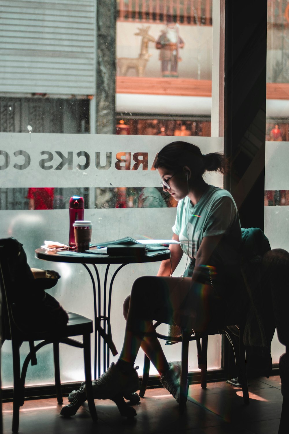 woman sitting alone by the glass window at Starbucks Cafe