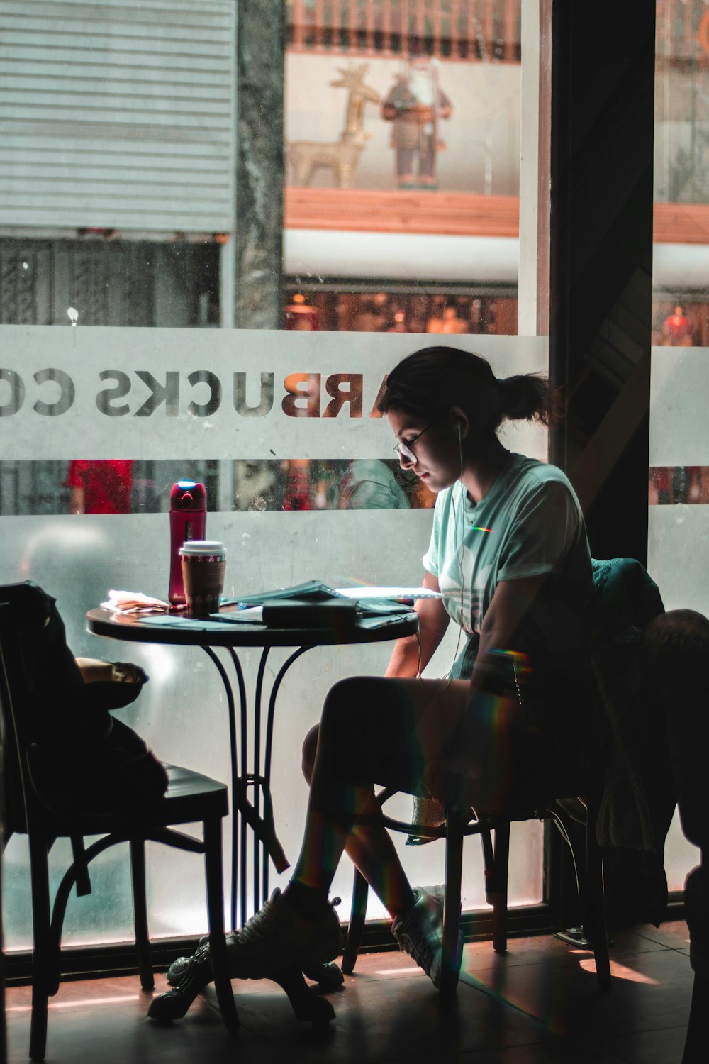 mulher sentada sozinha junto à janela de vidro no Starbucks Cafe