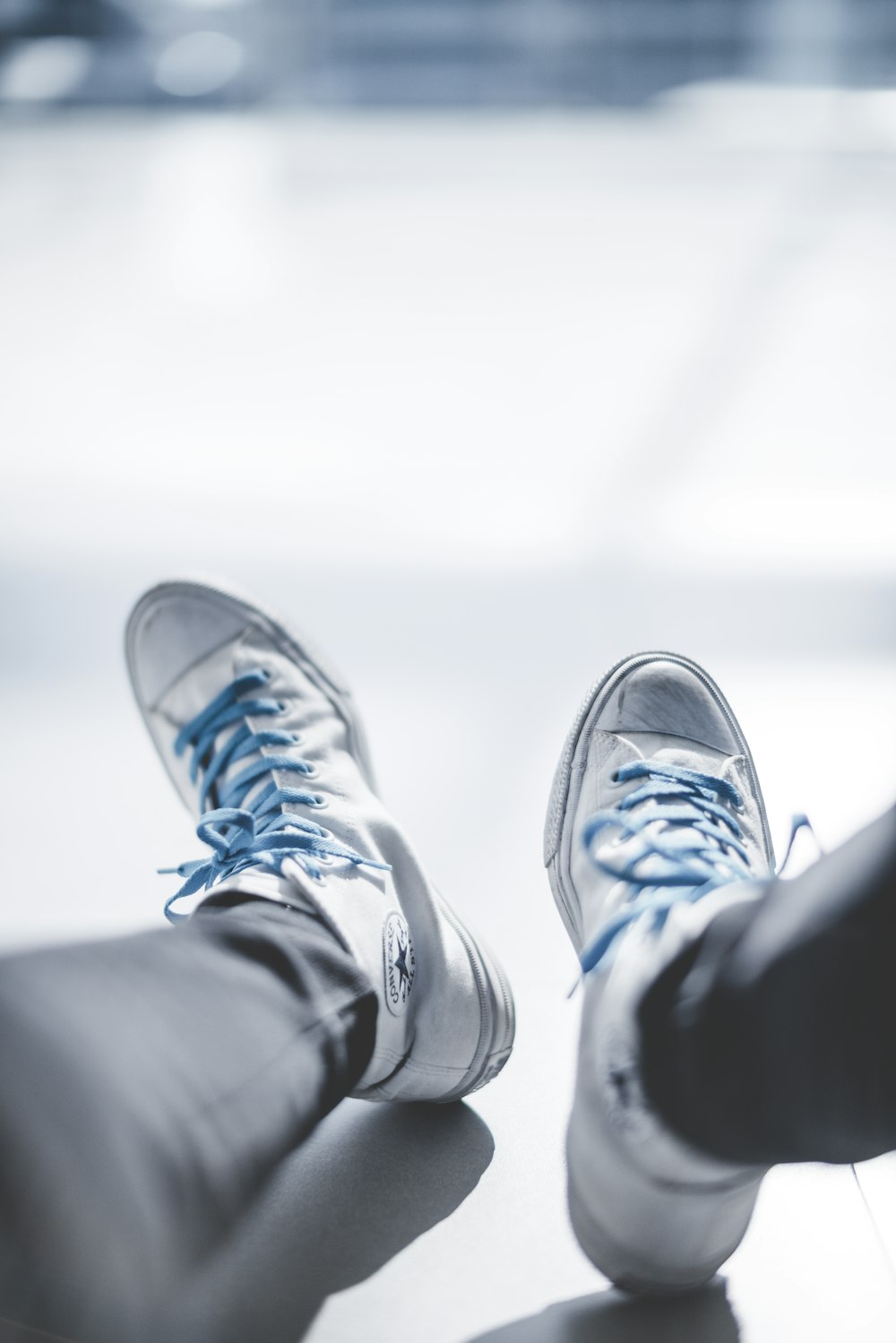fotografía de enfoque selectivo de una persona que lleva zapatillas blancas Chuck Taylor Converse