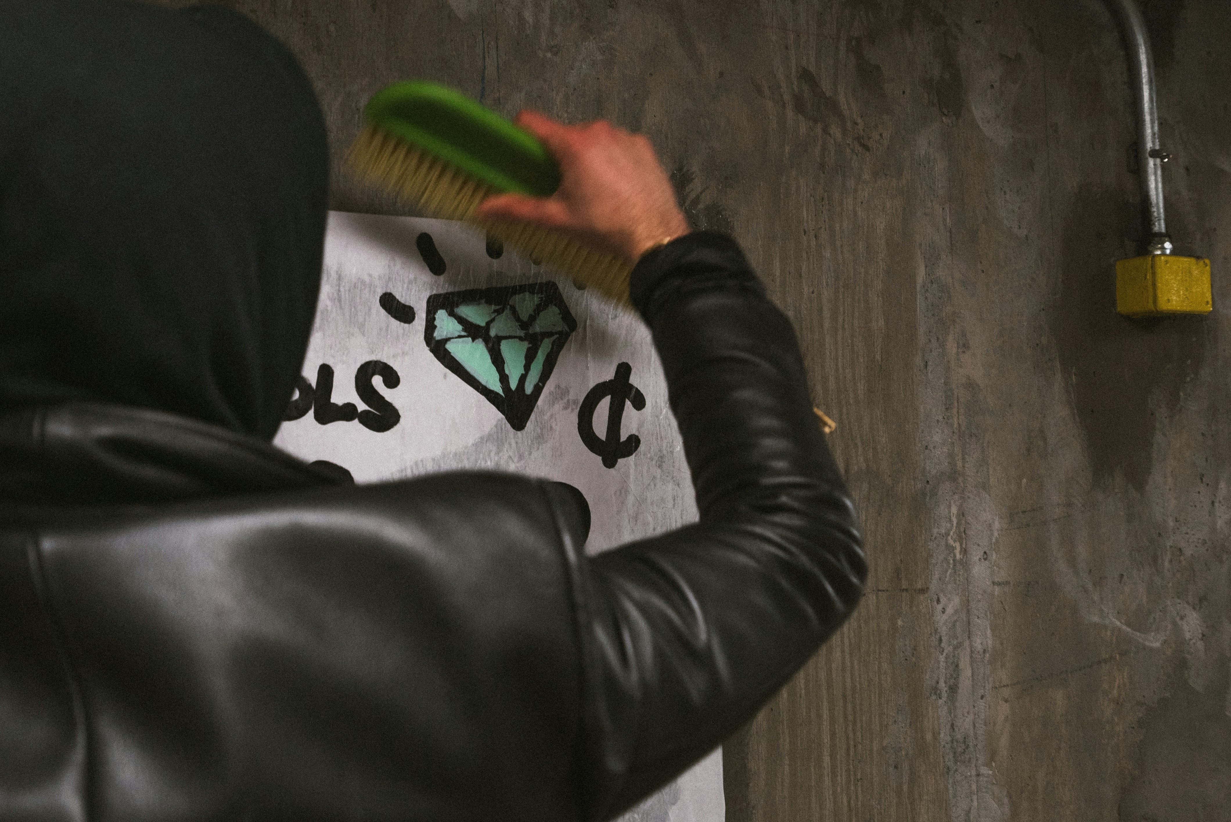 person wearing black jacket holding green brush