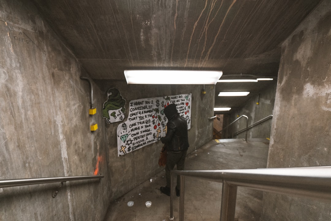 man standing beside poster under tunnel