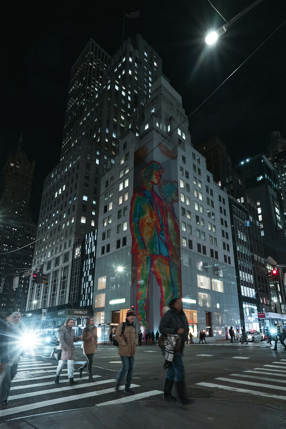 people walking on pedestrian lane with high-rise building background at night-time