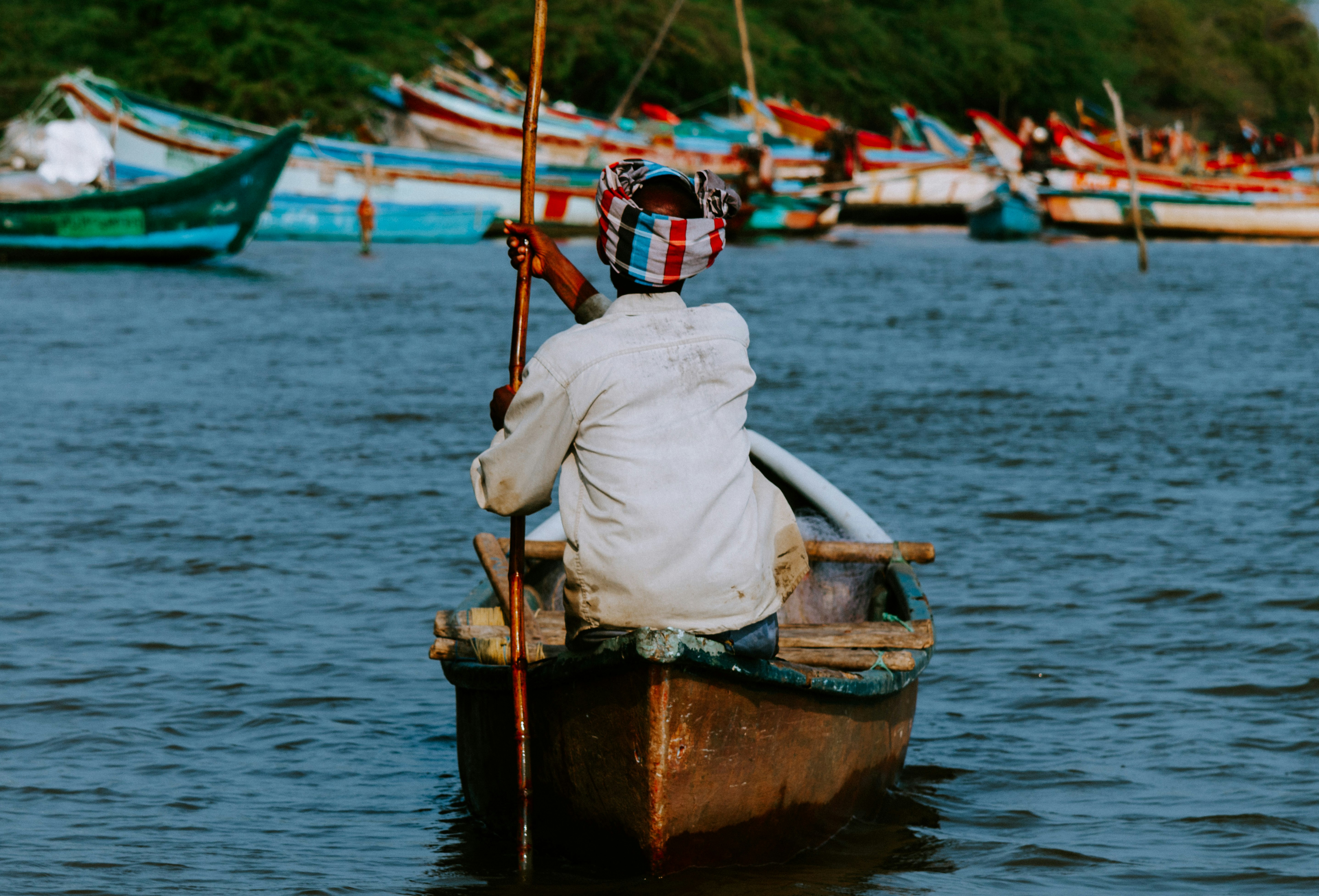 man sitting on wooden boat at middle of sea