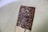 A close-up of a hand holding a granola bar with nuts and seeds visible.