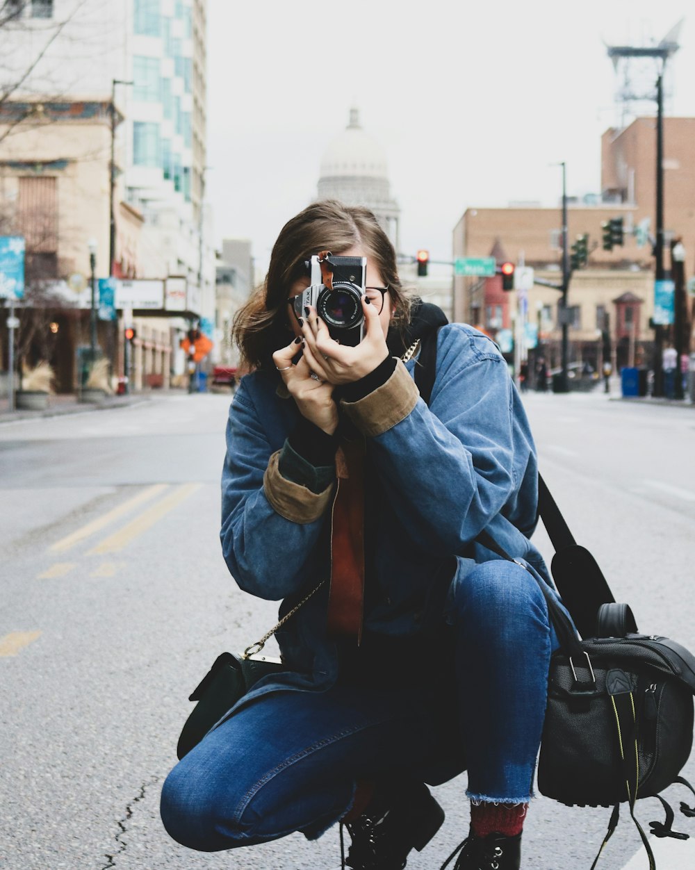 woman in blue denim jeans taking picture on road