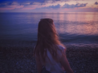 woman facing sea under cloudy sky