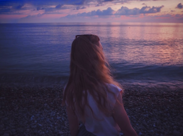 woman facing sea under cloudy sky