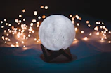Close-up of a softly glowing moon-inspired lamp casting gentle shadows.