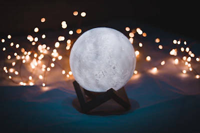 Close-up of a softly glowing moon-inspired lamp casting gentle shadows.