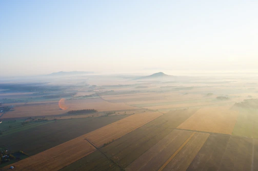 Aerial shot of the NA Farmhouse plots with lush greenery and fog.
