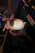 A smiling young man holding a latte art cup inside a cozy coffee academy classroom.