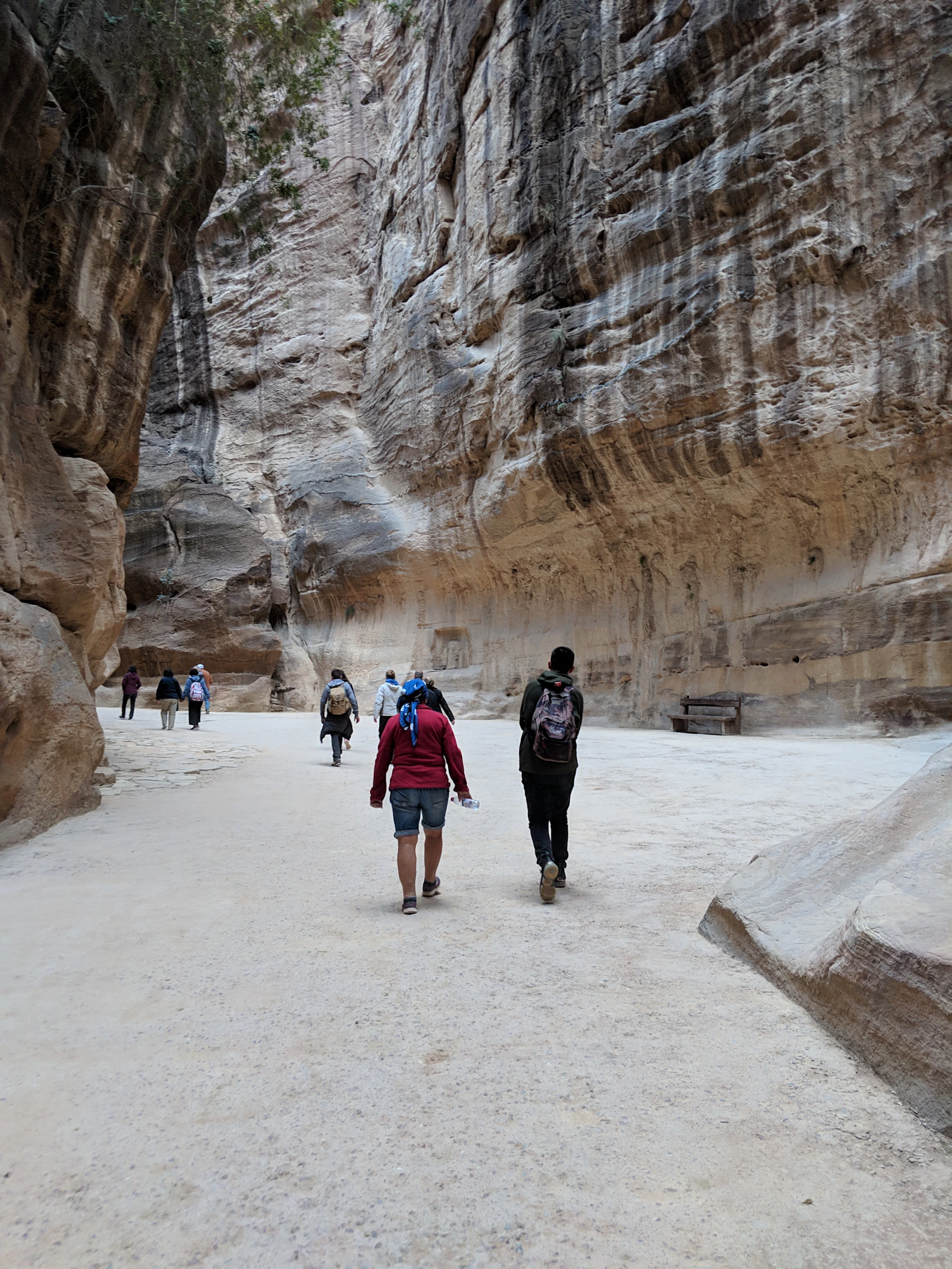Guests enjoying a quiet hike through a narrow, winding canyon with textured stone walls glowing in the afternoon sun.