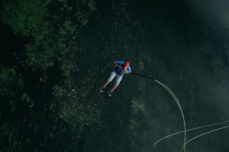 man jumps in body of water with safety rope