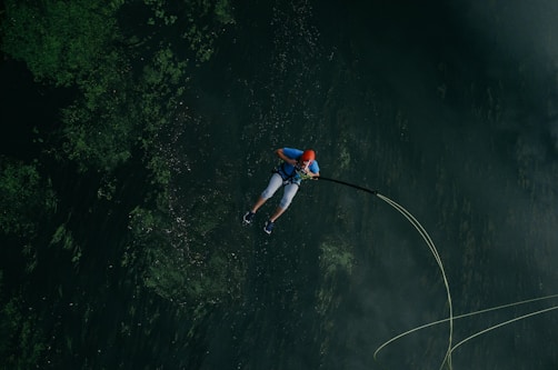 man jumps in body of water with safety rope
